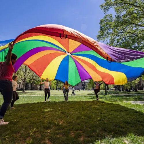 students with a rainbow parachute on campus