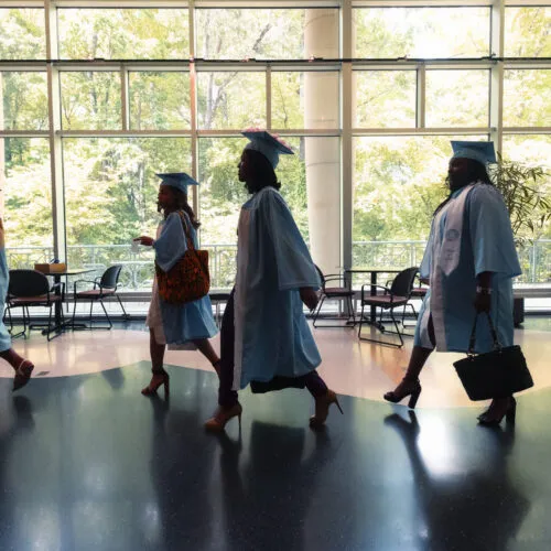 Graduating students walking through a hallway.