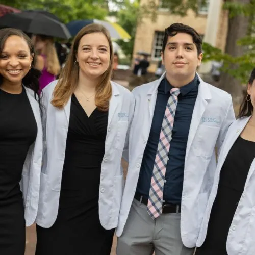 Four School of Medicine students standing together in white coats