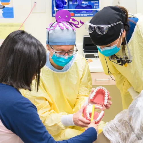 Two doctors in medical garb explain a dental procedure to a patient.