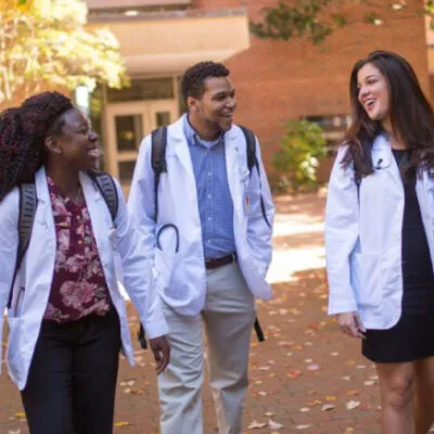 Students walking outside wearing white lab coats
